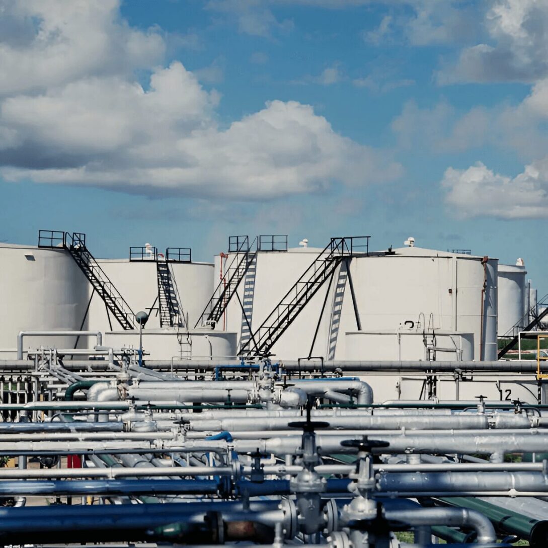 A large white tank in the middle of an oil field.